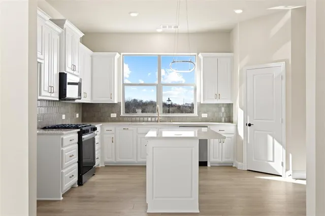 a kitchen with stainless steel appliances granite countertop a stove a sink and a refrigerator