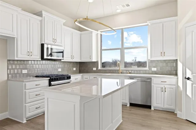a kitchen with stainless steel appliances granite countertop a stove and white cabinets
