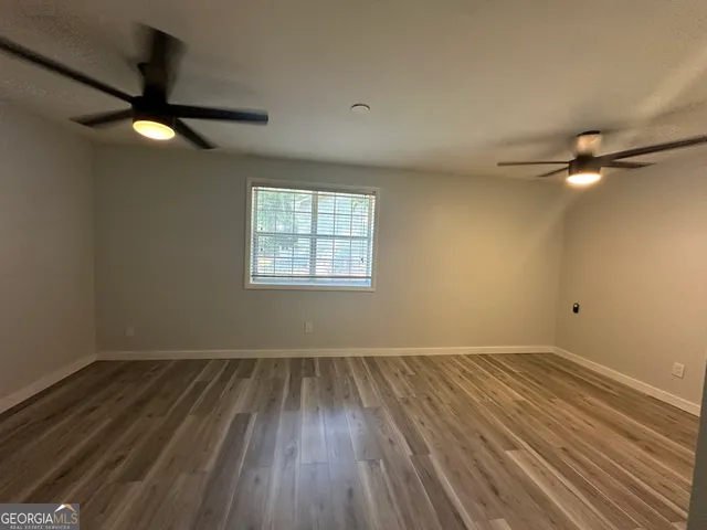 an empty room with wooden floor fan and windows