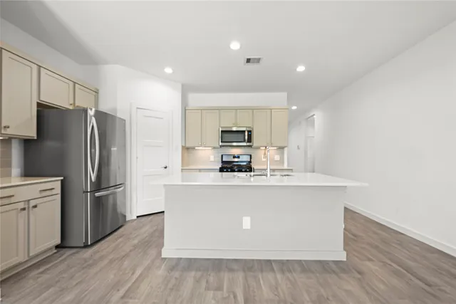 a kitchen with stainless steel appliances a refrigerator and a stove top oven
