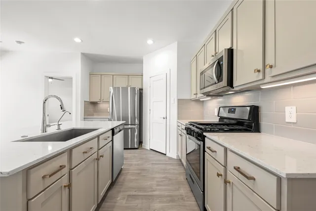 a kitchen with stainless steel appliances granite countertop a sink a stove and a refrigerator