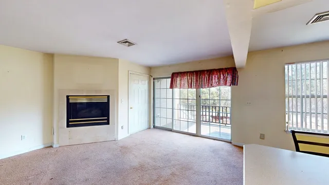 a view of an empty room with a window and fire place