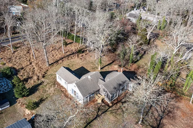 an aerial view of a house with yard and covered with trees