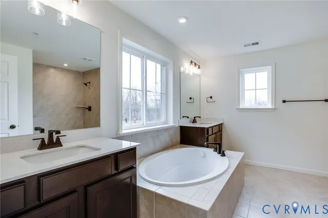 a spacious bathroom with a tub sink and mirror
