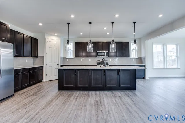 a large kitchen with stainless steel appliances kitchen island granite countertop a stove a sink and a microwave