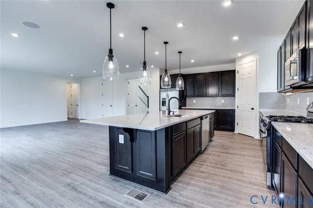 a kitchen with stainless steel appliances a sink a stove top oven a counter space and cabinets