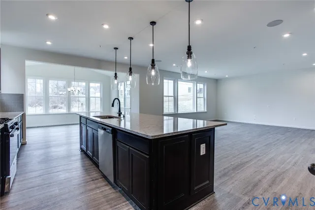 a kitchen with stainless steel appliances granite countertop wooden floors wooden cabinets a center island and a wooden floor