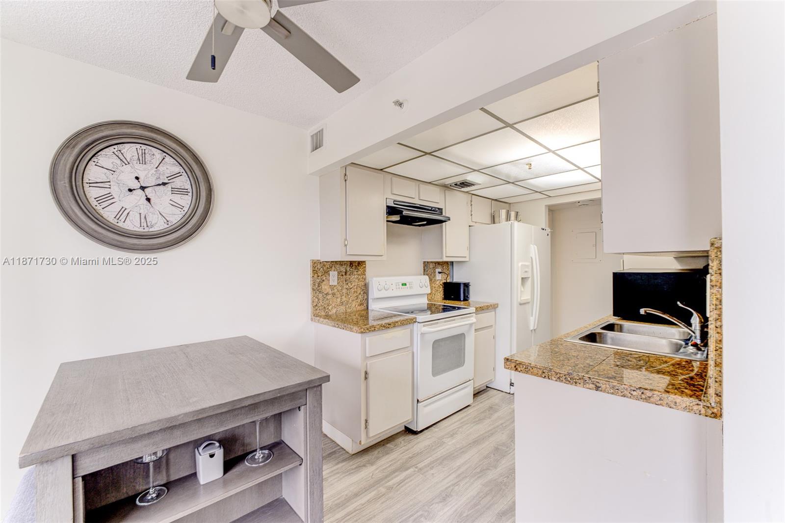 210 174th Street, Unit 312 Sunny Isles Beach, FL 33160 - Photo 9 of 16 a kitchen with a stove and a clock on the wall