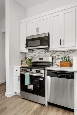 a kitchen with stainless steel appliances granite countertop a stove a microwave and a white cabinets