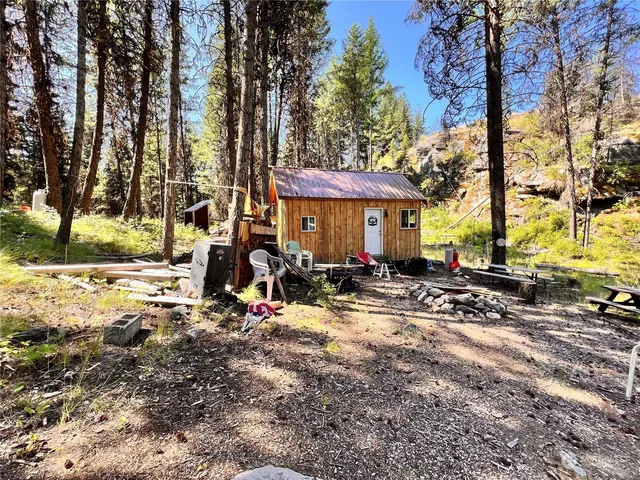 a view of a house with large trees and sitting area
