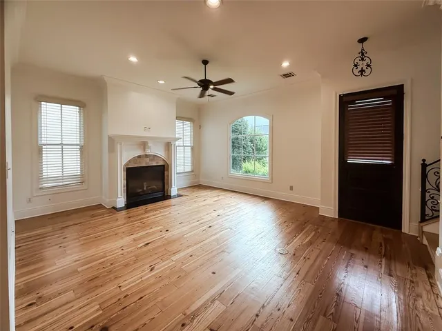 an empty room with windows fireplace and wooden floor