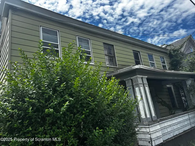 a front view of a house with plants