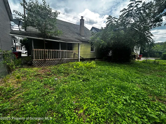 a view of a house with a small yard and a large tree