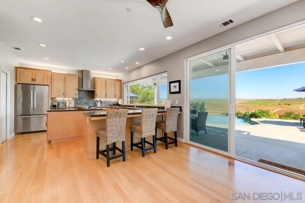 1834 Winterwarm Drive Fallbrook, CA 92028 - Photo 12 of 49 a kitchen with stainless steel appliances refrigerator wooden floor dining table and chairs