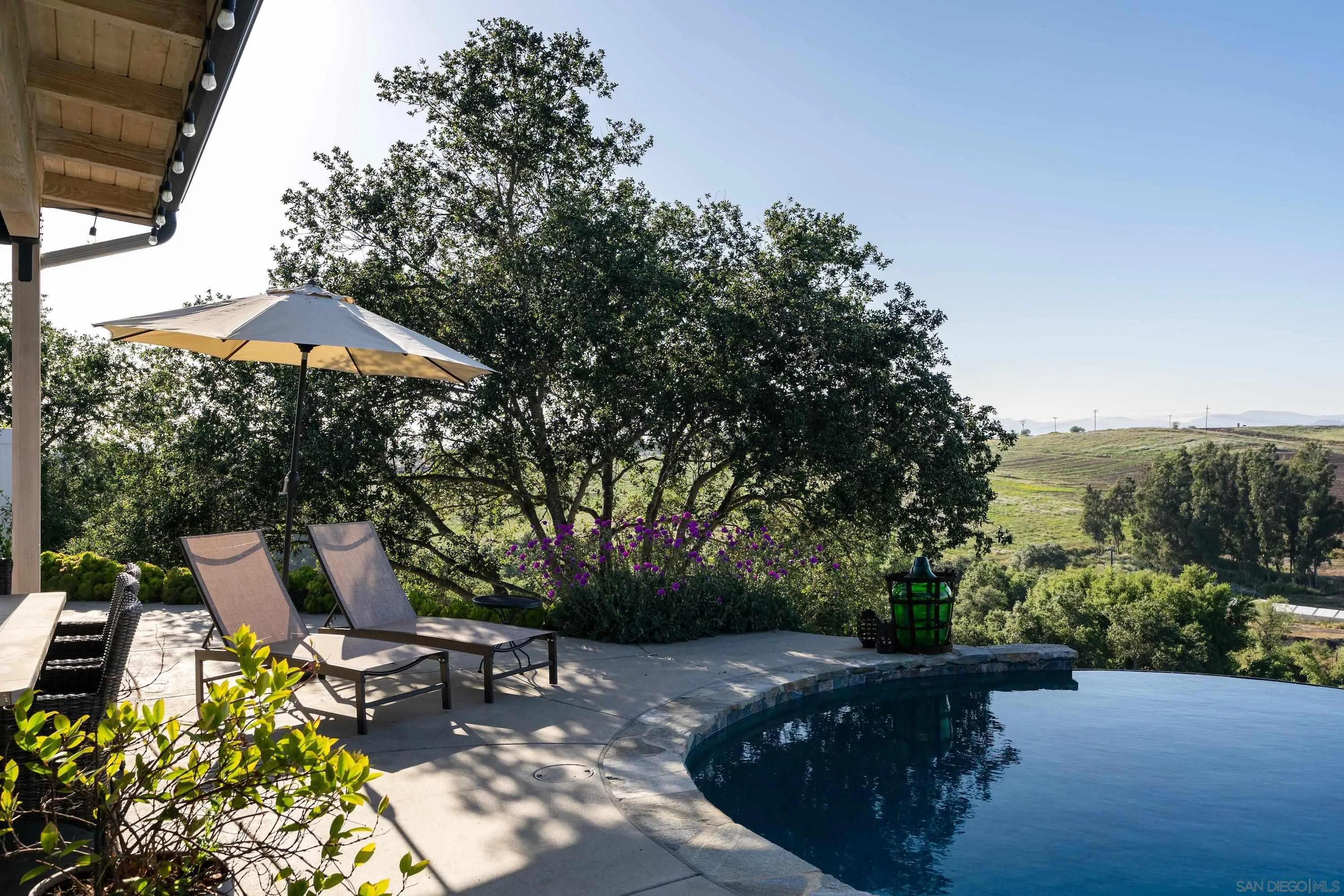 1834 Winterwarm Drive Fallbrook, CA 92028 - Photo 46 of 49 a view of a patio with table and chairs under an umbrella with large trees