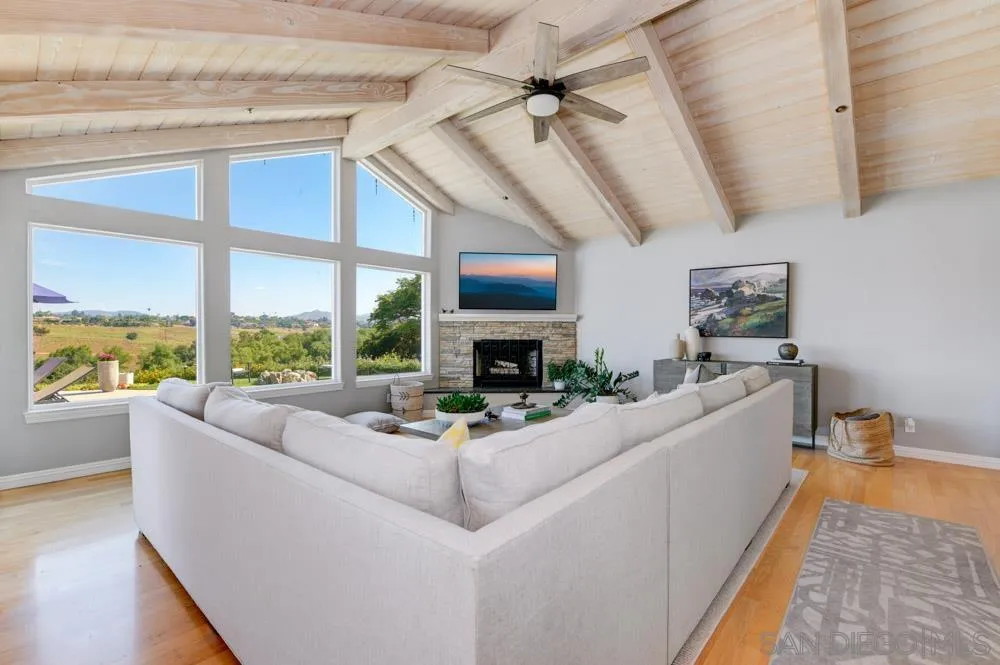 1834 Winterwarm Drive Fallbrook, CA 92028 - Photo 6 of 49 a living room with furniture large windows a flat screen tv and a fireplace