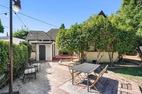 a patio with table and chairs and potted plants