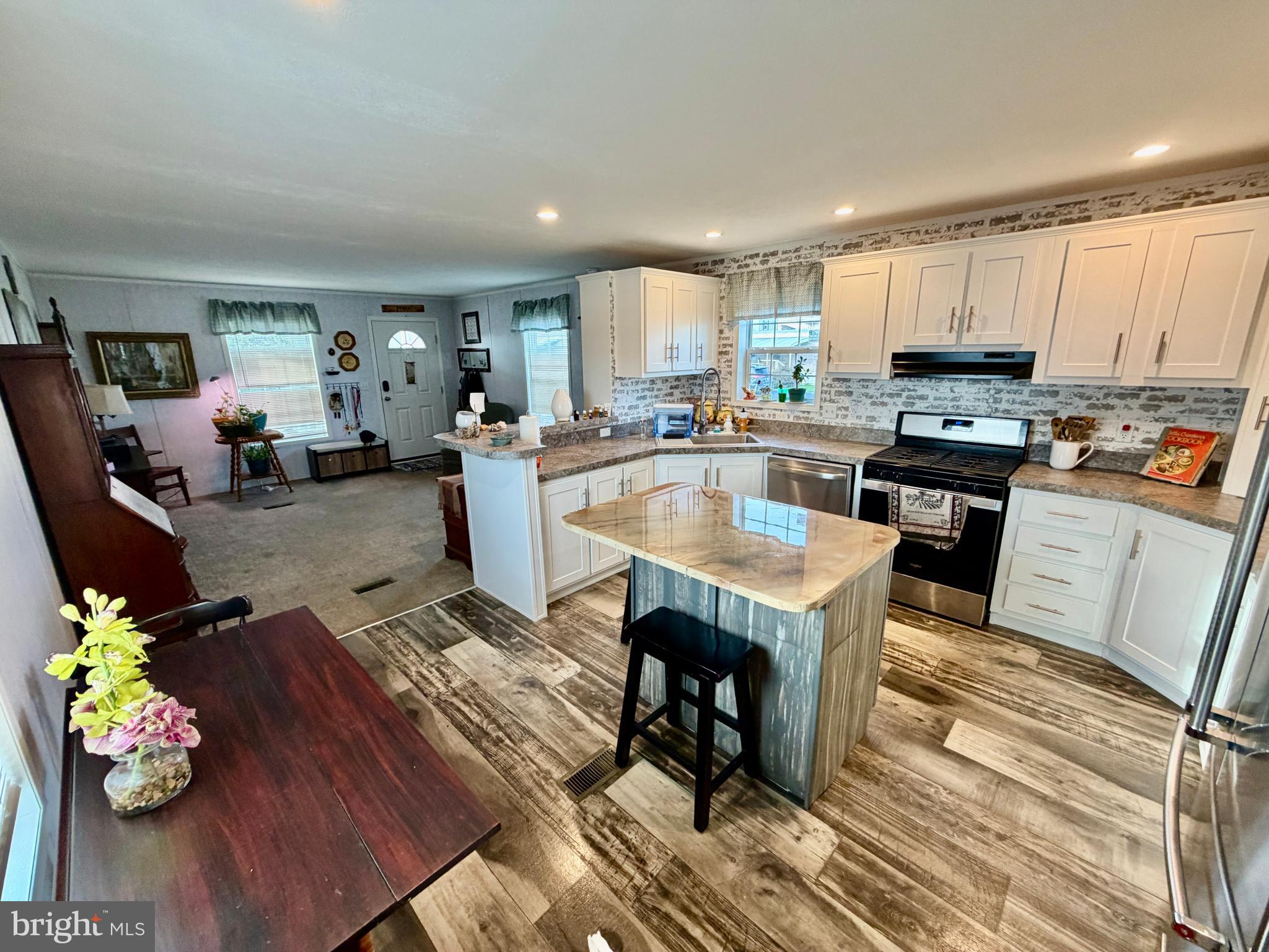 92 Ridgewood Manor Manheim, PA 17545 - Photo 13 of 22 a kitchen with stainless steel appliances granite countertop a refrigerator dining table and chairs with wooden floor