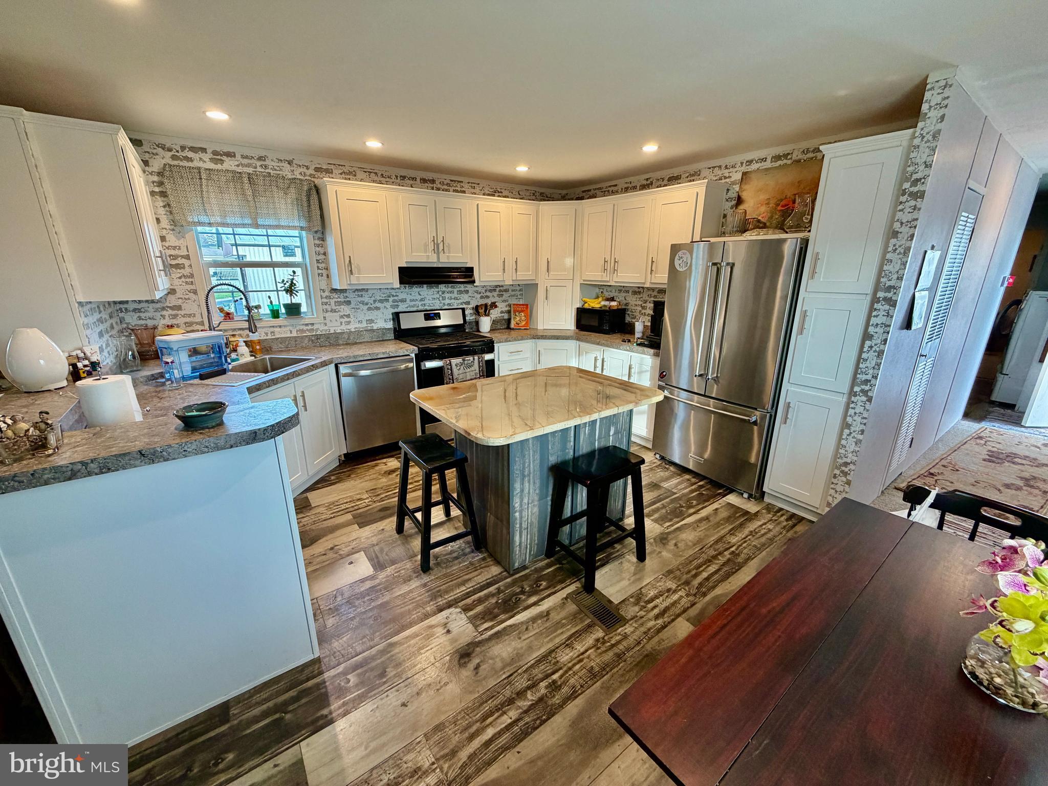 92 Ridgewood Manor Manheim, PA 17545 - Photo 10 of 22 a kitchen with stainless steel appliances granite countertop a refrigerator a sink dishwasher a stove a dining table and chairs with wooden floor