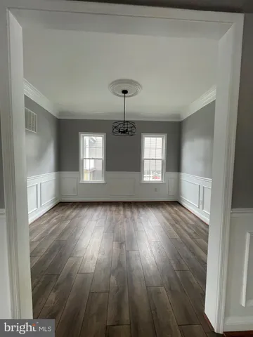 a view of empty room with window and wooden floor