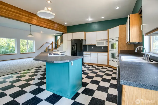 a kitchen with stainless steel appliances kitchen island granite countertop a sink and a refrigerator