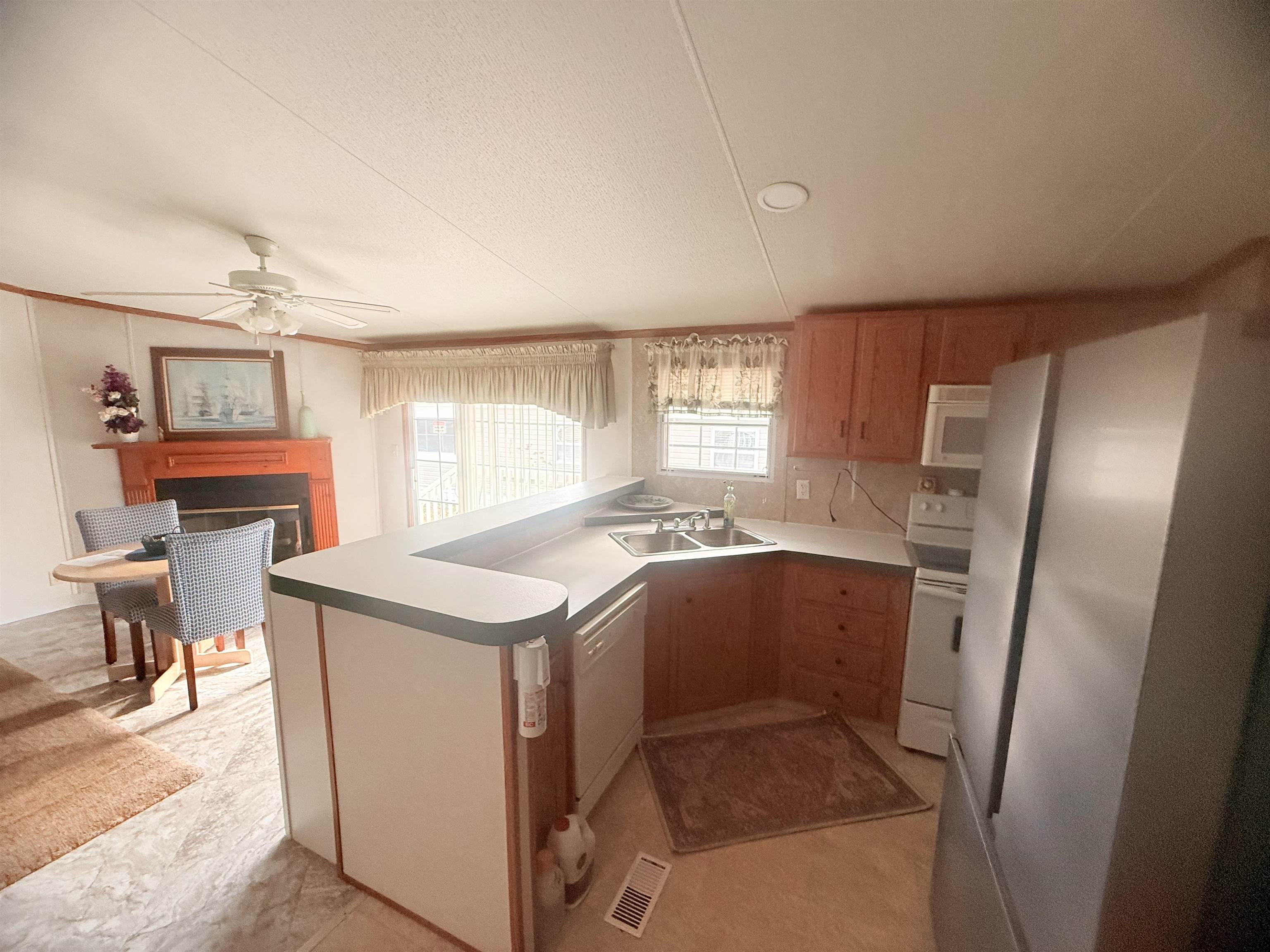 5 Buccaneer Street Murrells Inlet, SC 29576 - Photo 11 of 30 Kitchen with white appliances, a peninsula, a ceiling fan, light countertops, and a fireplace