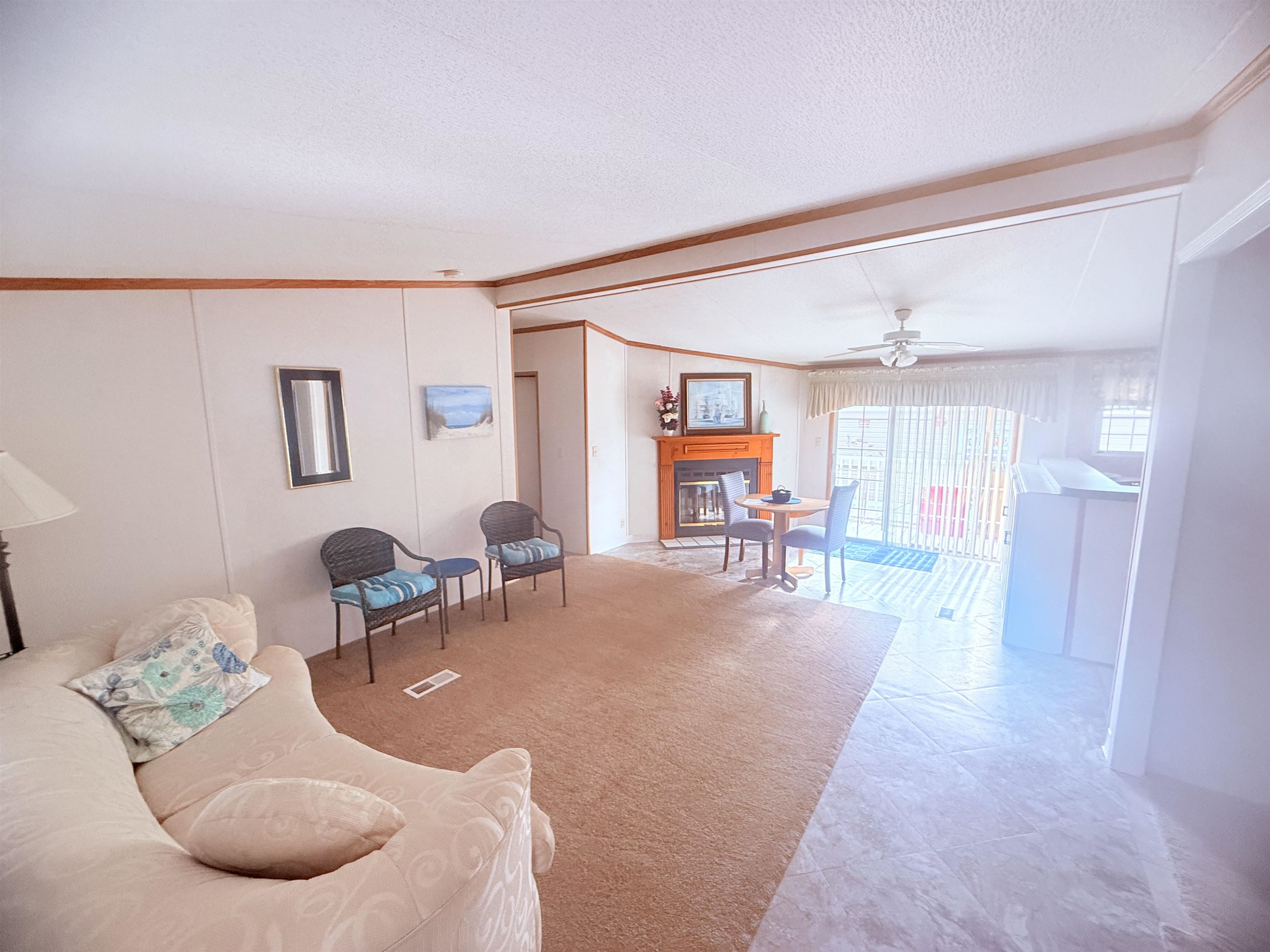 5 Buccaneer Street Murrells Inlet, SC 29576 - Photo 7 of 30 Living room with ornamental molding, vaulted ceiling, a glass covered fireplace, a ceiling fan, and a textured ceiling