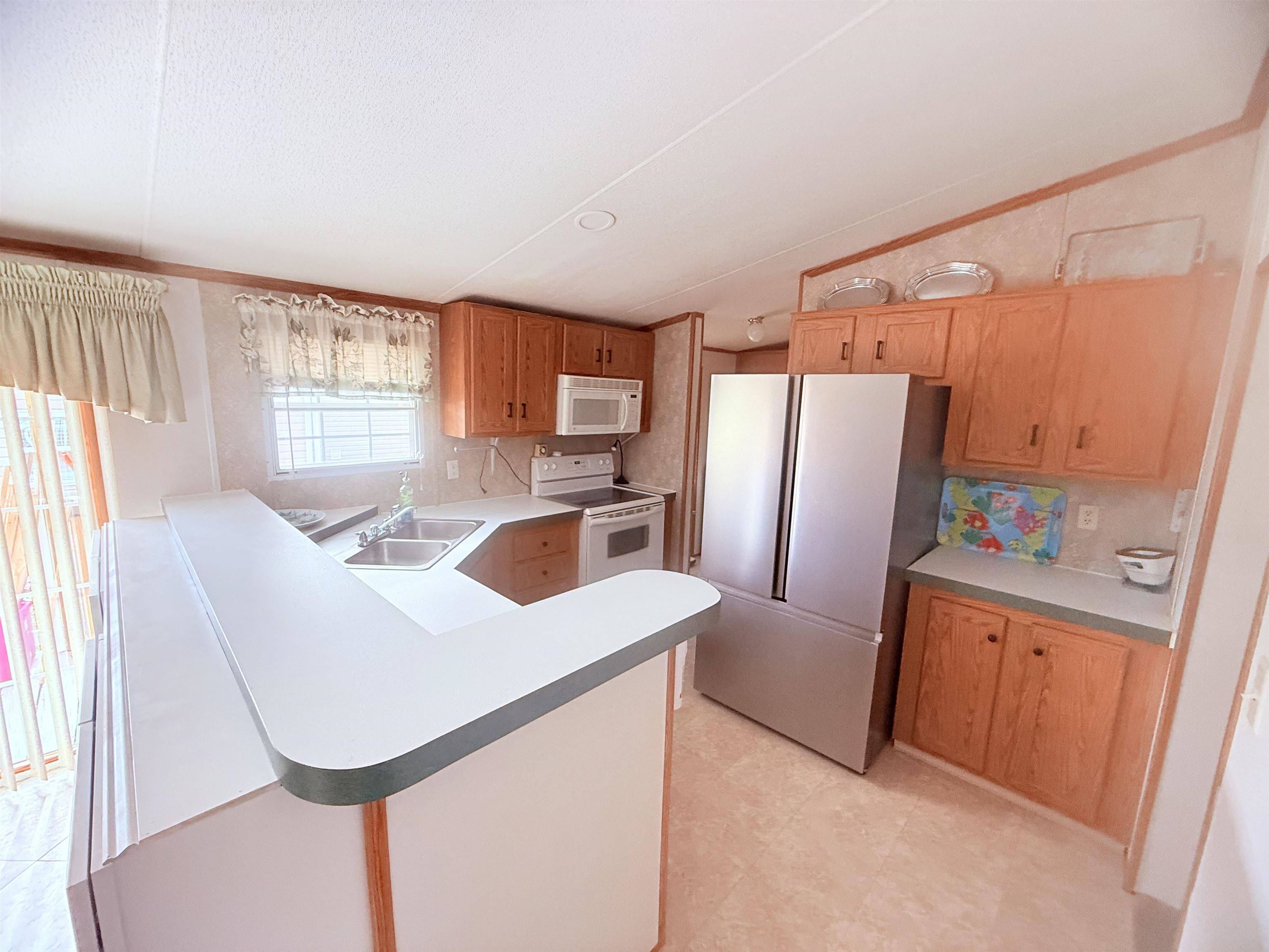 5 Buccaneer Street Murrells Inlet, SC 29576 - Photo 10 of 30 Kitchen featuring white appliances, light countertops, a peninsula, and brown cabinets