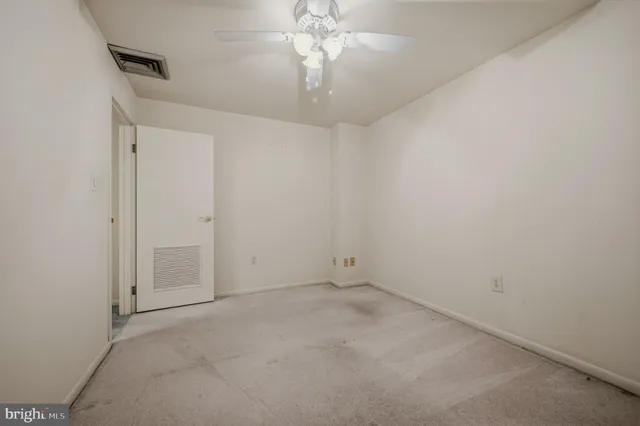 an empty room with a chandelier fan and closet area