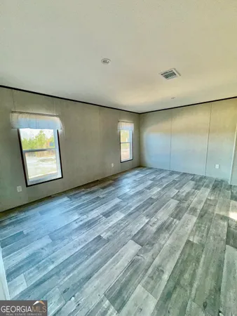 an empty room with wooden floor and windows
