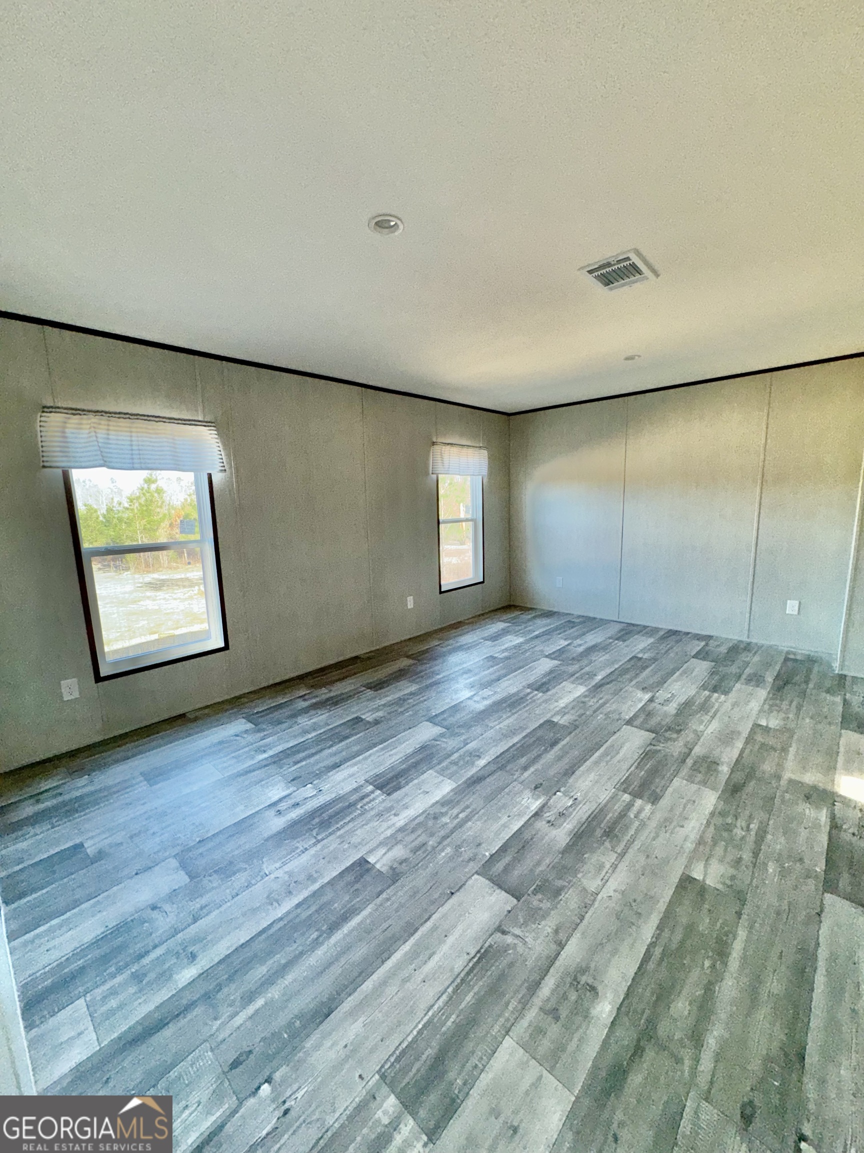 545 Ben Jackson Road Vidalia, GA 30474 - Photo 9 of 25 an empty room with wooden floor and windows