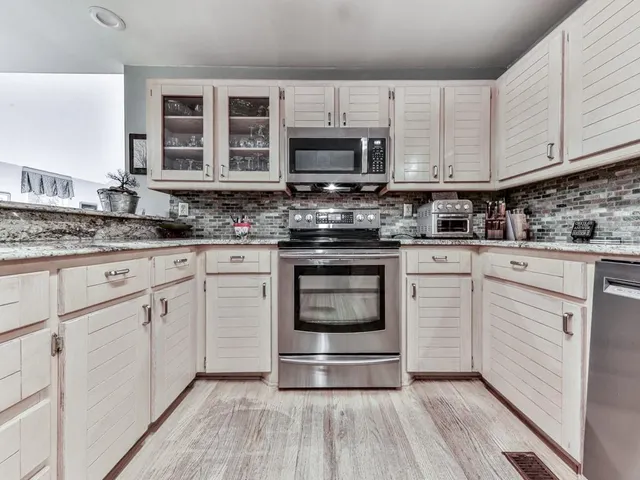 a kitchen with stainless steel appliances granite countertop a stove and white cabinets