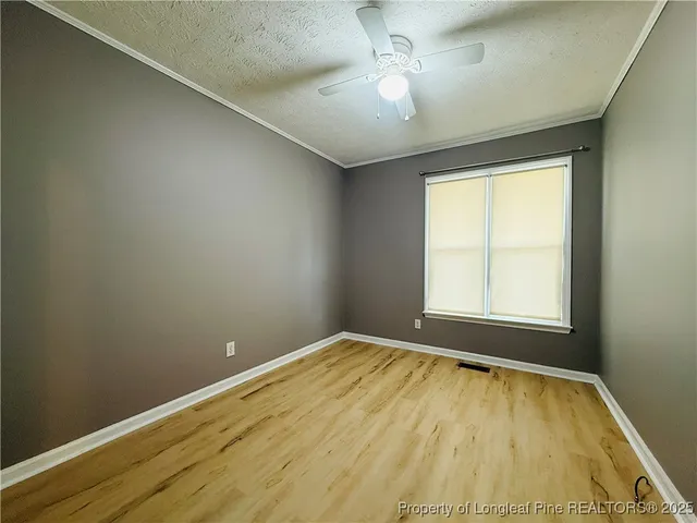 an empty room with a chandelier fan and windows