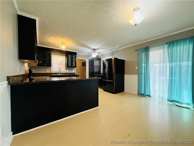 a kitchen with stainless steel appliances kitchen island granite countertop a refrigerator a stove and a sink with wooden floor