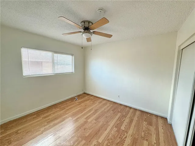 an empty room with wooden floor fan and windows