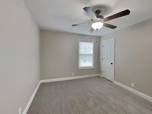 an empty room with a window and a fan