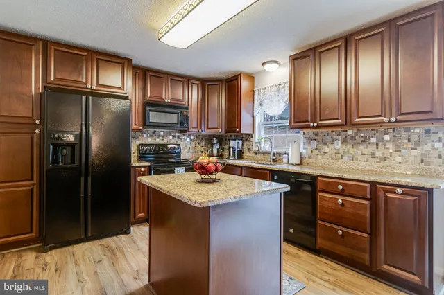 a kitchen with stainless steel appliances granite countertop a refrigerator a sink a stove and dishwasher