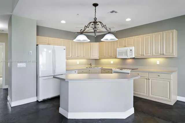 a kitchen with kitchen island granite countertop a sink a counter space appliances and cabinets
