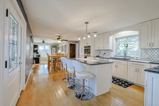 a kitchen with a refrigerator a stove top oven a sink dishwasher and white cabinets with wooden floor