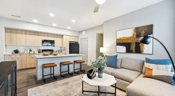 a living room with stainless steel appliances furniture and a kitchen view
