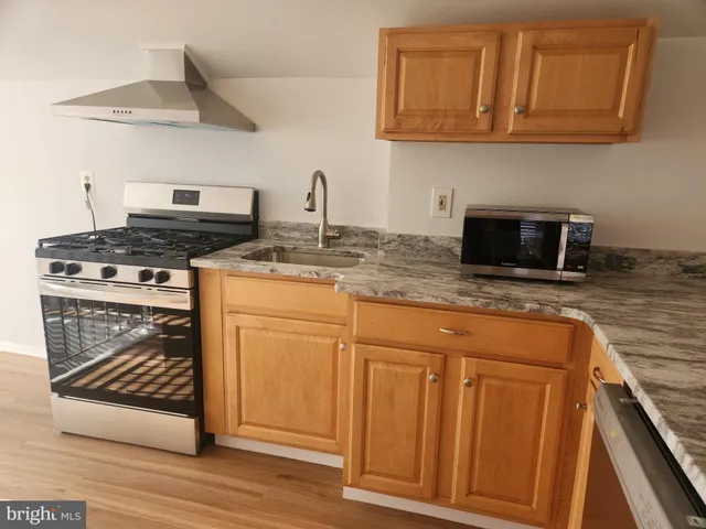a kitchen with granite countertop a stove top oven microwave and cabinets