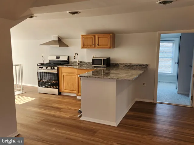 a kitchen with stainless steel appliances granite countertop a sink stove and wooden floor