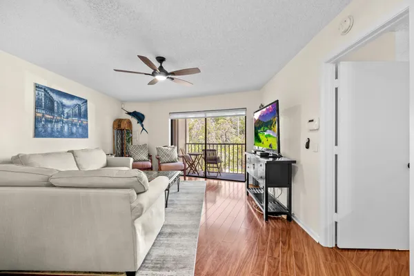 a living room with furniture floor to ceiling window and a flat screen tv