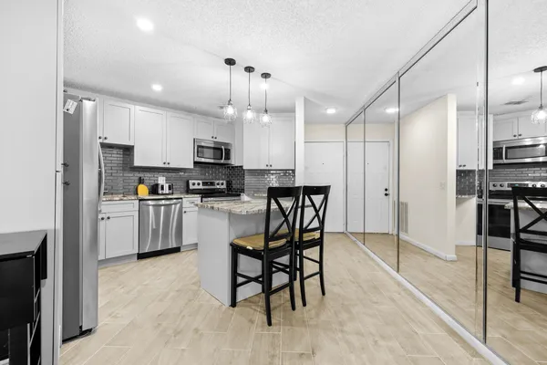 a kitchen with stainless steel appliances kitchen island granite countertop a stove a refrigerator a oven a sink with a dining table and chairs