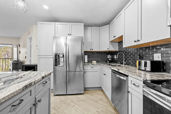 a kitchen with stainless steel appliances granite countertop a refrigerator a stove and a sink