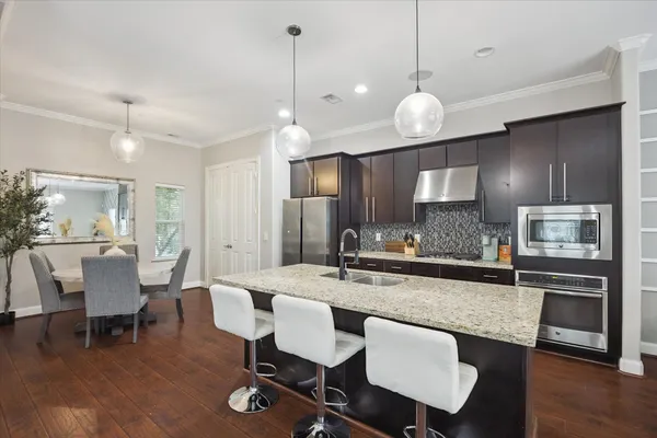 a kitchen with a dining table chairs and wooden floor
