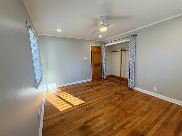 an empty room with wooden floor fan and windows