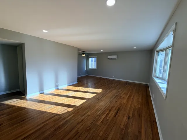 a bedroom with wooden floor and window
