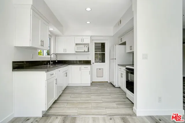 a kitchen with granite countertop a refrigerator and a sink