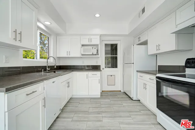 a kitchen with granite countertop white cabinets and white appliances